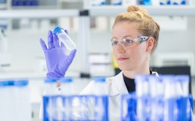 Female lab scientist inspecting LNP suspension in flask