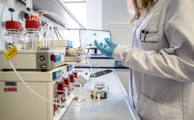 Female lab scientist operating high throughput LNP manufacturing setup