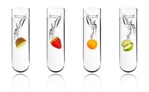 四个装满水的透明试管。每支试管中都装有一种不同的水果，滴入液体后，每支试管的顶部都会产生水花四溅的效果。