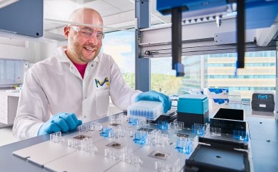 Male scientist placing components in the AAW™ automated assay workstation.